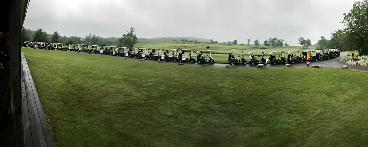 Golf carts lined up on grassy field