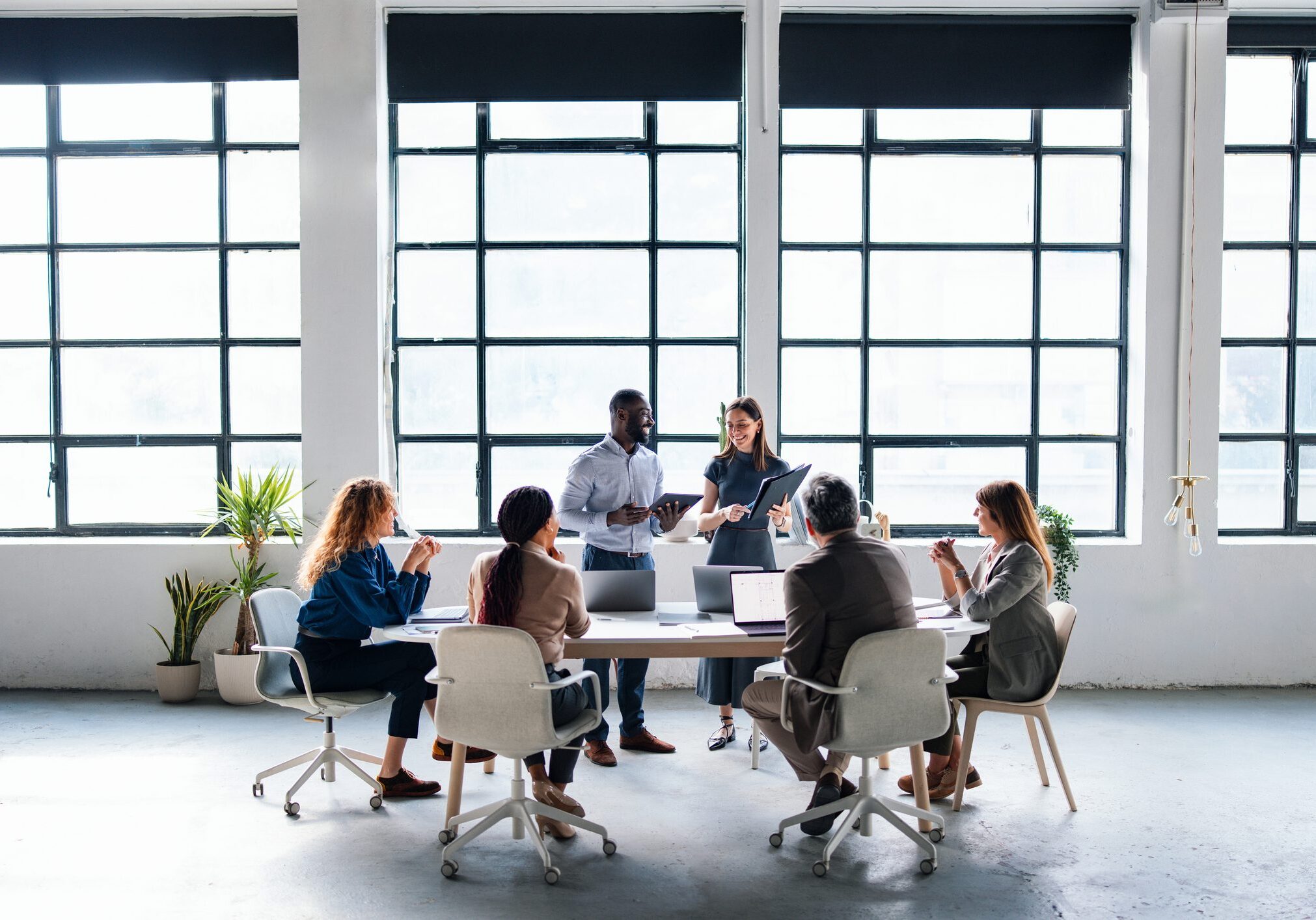 A diverse group of professionals collaborating in a modern office space, engaging in a productive team discussion to align project goals and ideas. Bright setting emphasizes team cooperation and innovative workplace spirit.